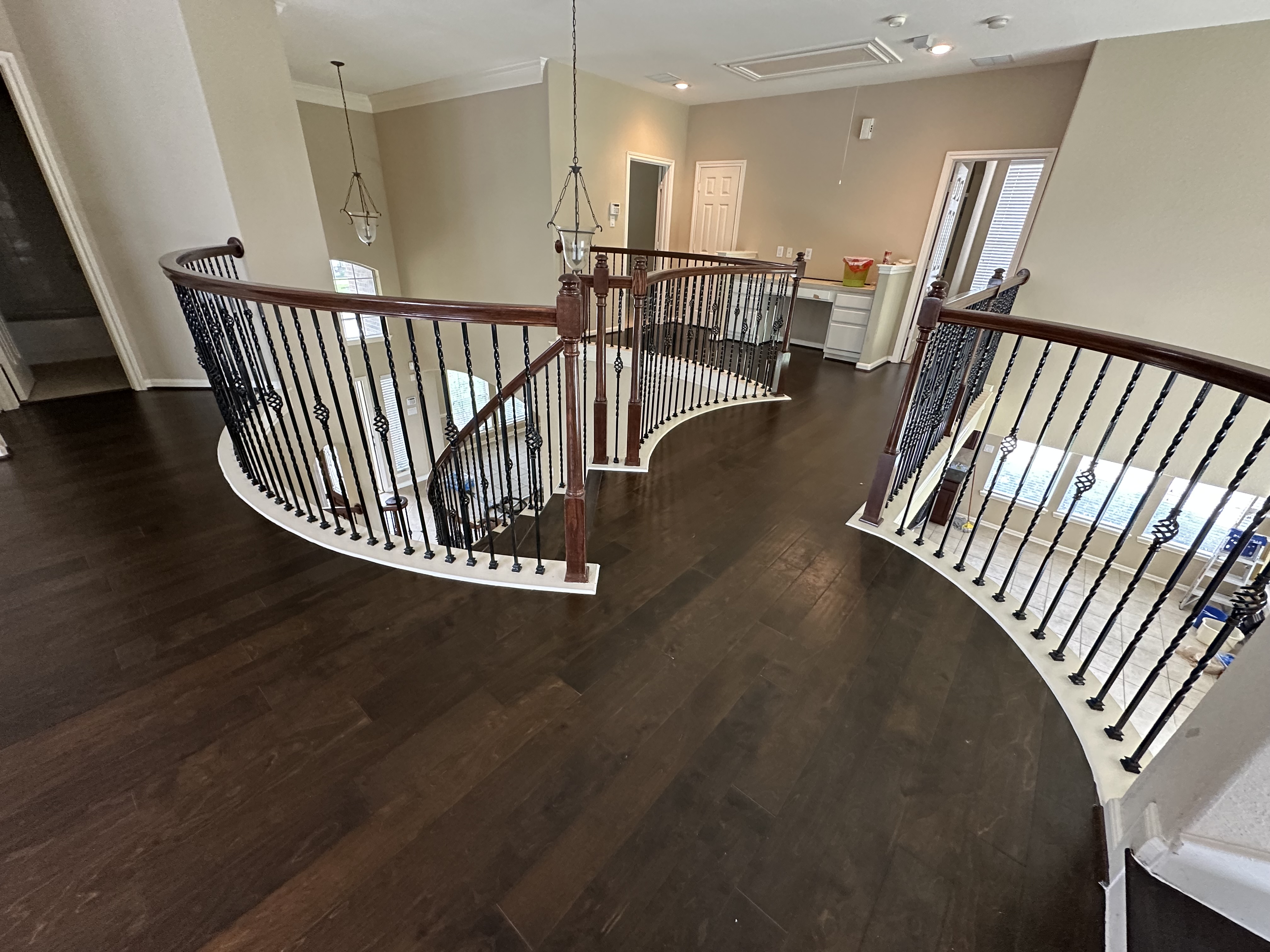 Curved dark hardwood staircase landing with iron balusters