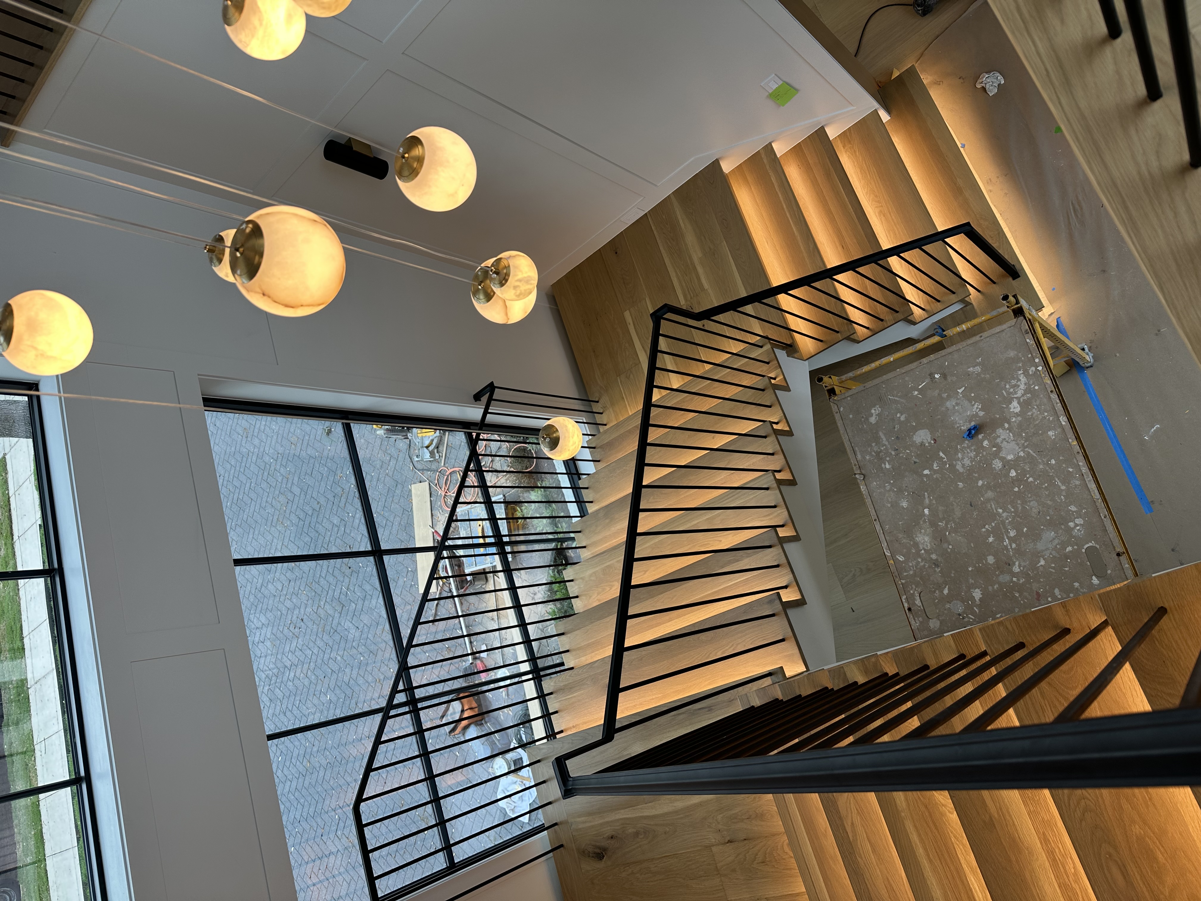 Modern floating white oak staircase with black metal railing and pendant lights