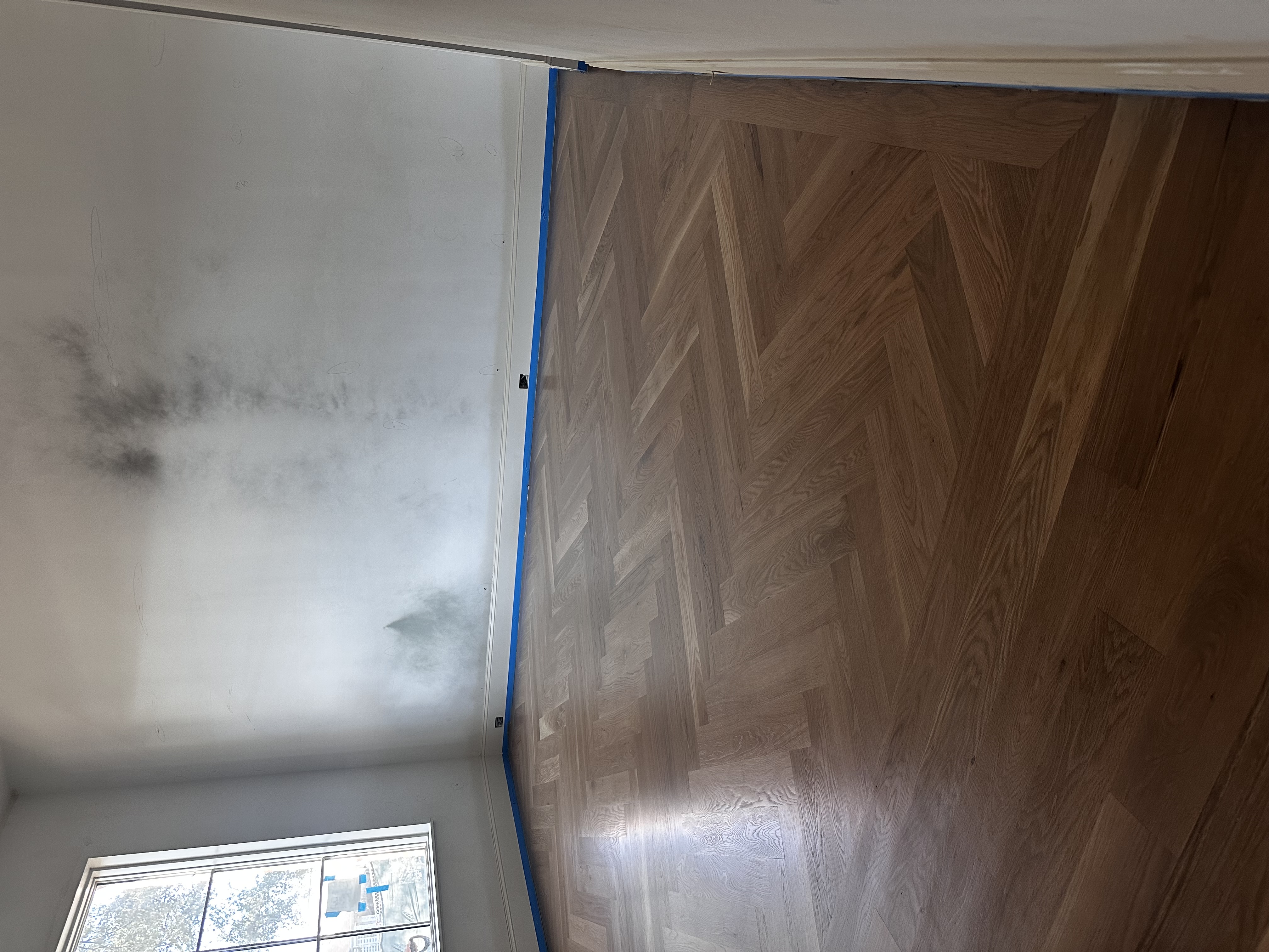 Light-stained herringbone white oak floor in an empty room