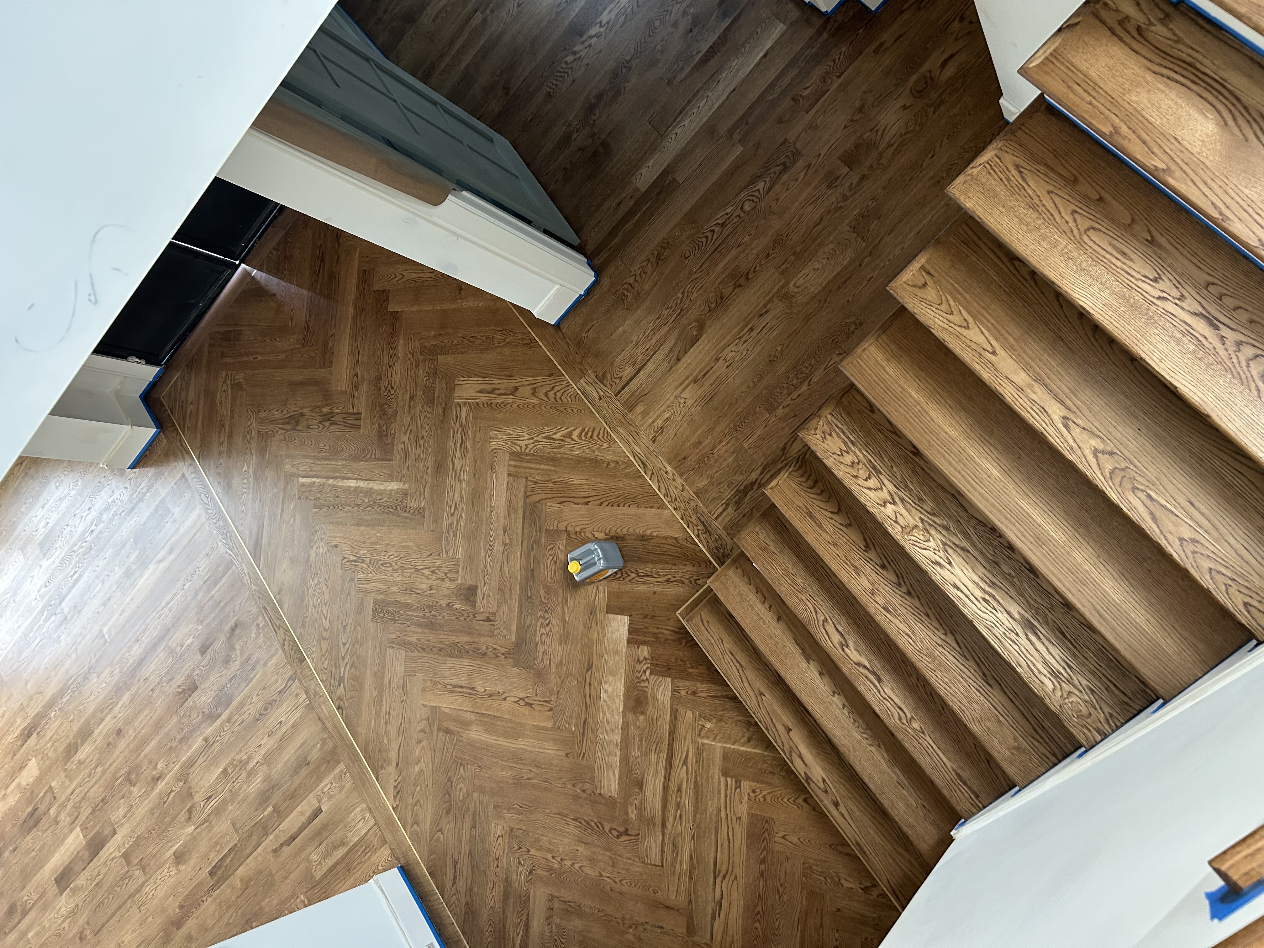 Overhead view of stained herringbone floor meeting a hardwood staircase