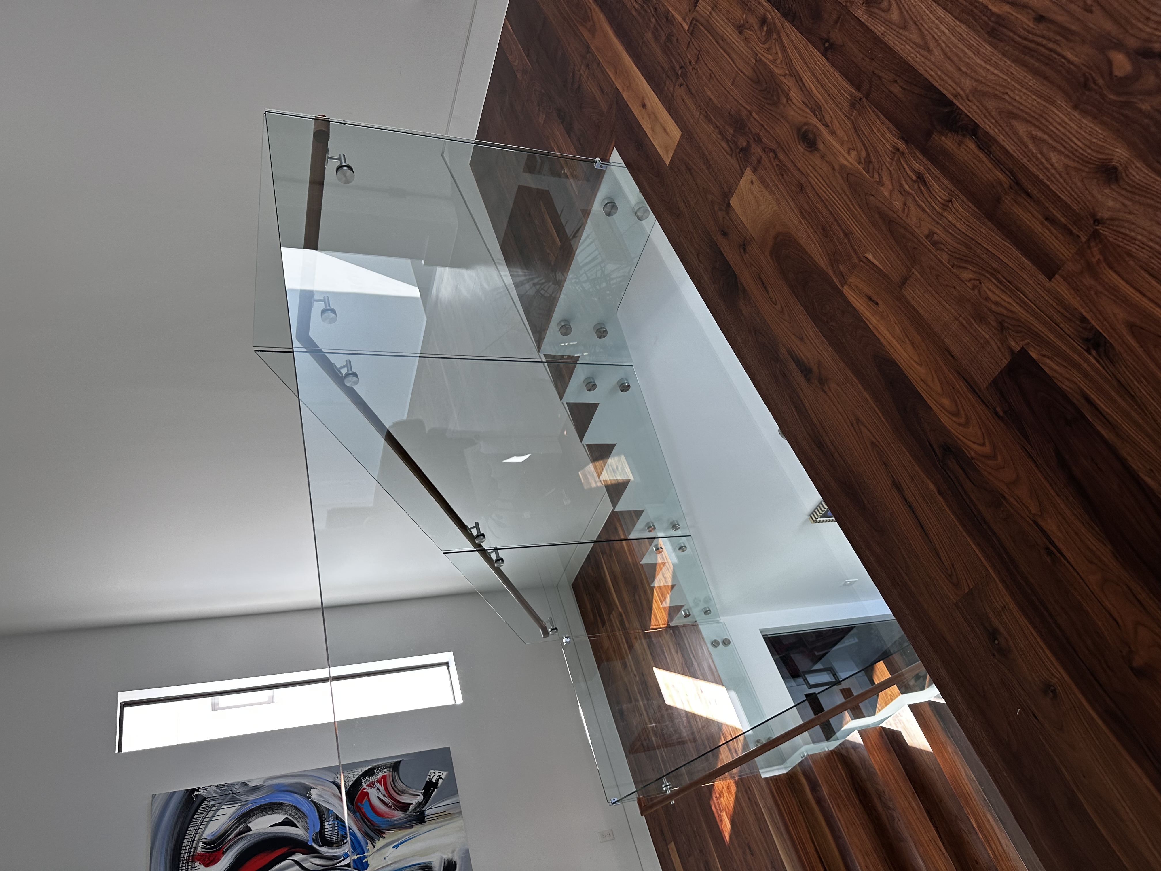 Walnut plank floor at a glass-railed staircase landing